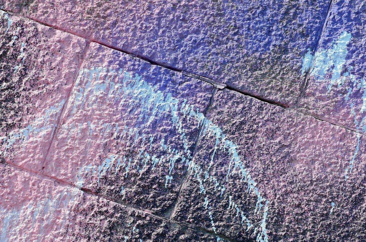 Fragment of graffiti drawings. The old wall decorated with paint stains in the style of street art culture. Colored background texture in purple tones photo