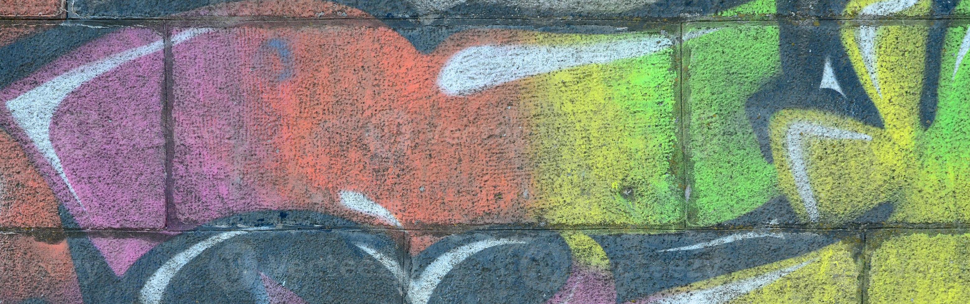 Fragment of graffiti drawings. The old wall decorated with paint stains in the style of street art culture. Multicolored background texture photo