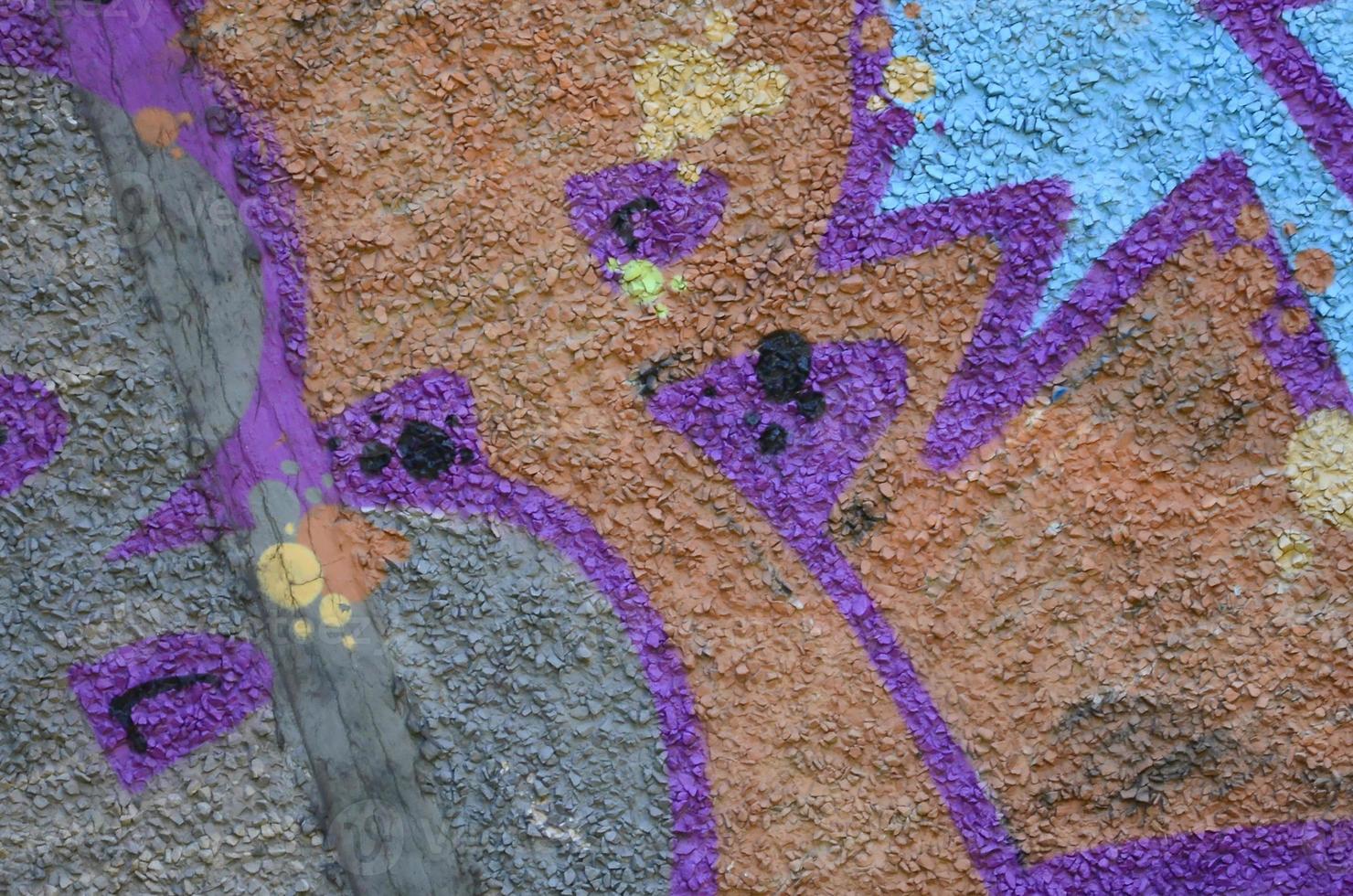 Fragment of graffiti drawings. The old wall decorated with paint stains in the style of street art culture. Colored background texture in warm tones photo