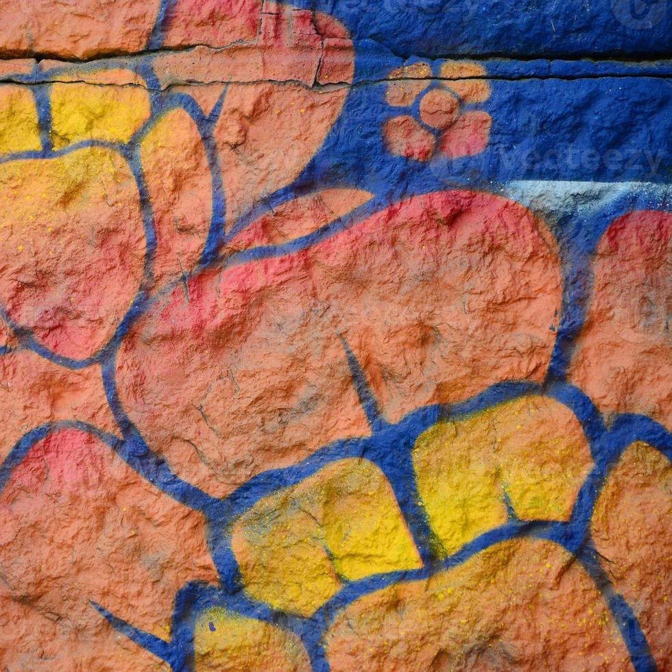 fragmento de dibujos de graffiti. la antigua muralla decorada con manchas de pintura al estilo de la cultura del arte callejero. flor naranja foto