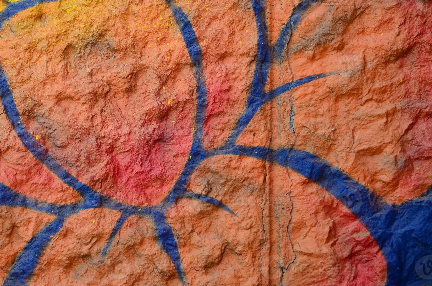 fragmento de dibujos de graffiti. la antigua muralla decorada con manchas de pintura al estilo de la cultura del arte callejero. flor naranja foto