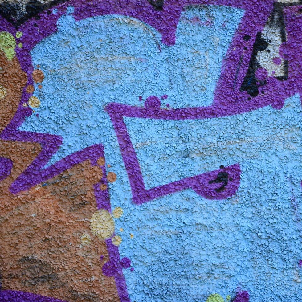 Fragment of graffiti drawings. The old wall decorated with paint stains in the style of street art culture. Colored background texture in warm tones photo