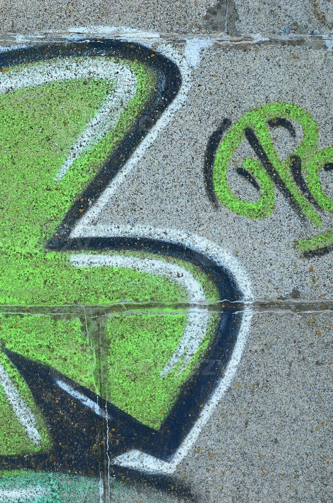 fragmento de dibujos de graffiti. la antigua muralla decorada con manchas de pintura al estilo de la cultura del arte callejero. textura de fondo coloreada en tonos verdes foto