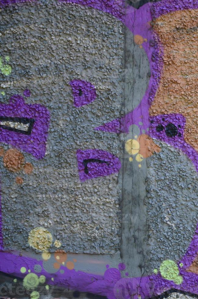 Fragment of graffiti drawings. The old wall decorated with paint stains in the style of street art culture. Colored background texture in warm tones photo
