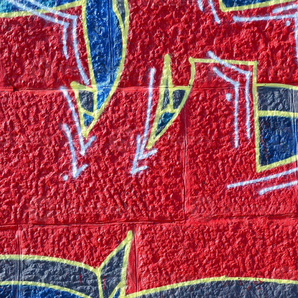 Fragment of graffiti drawings. The old wall decorated with paint stains in the style of street art culture. Colored background texture in warm tones photo