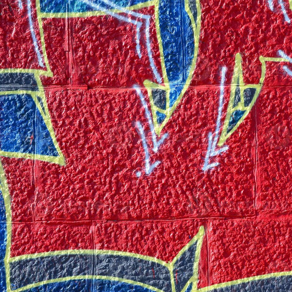 Fragment of graffiti drawings. The old wall decorated with paint stains in the style of street art culture. Colored background texture in warm tones photo