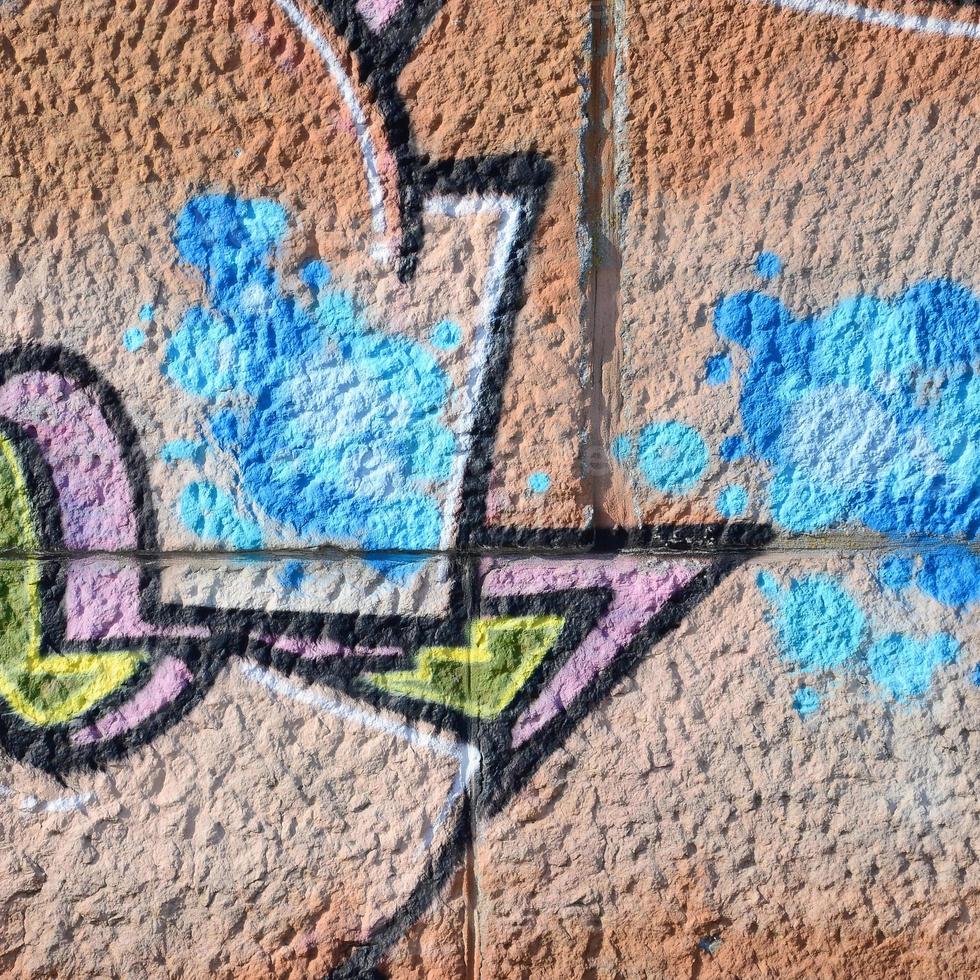 fragmento de dibujos de graffiti. la antigua muralla decorada con manchas de pintura al estilo de la cultura del arte callejero. textura de fondo coloreada en tonos cálidos foto