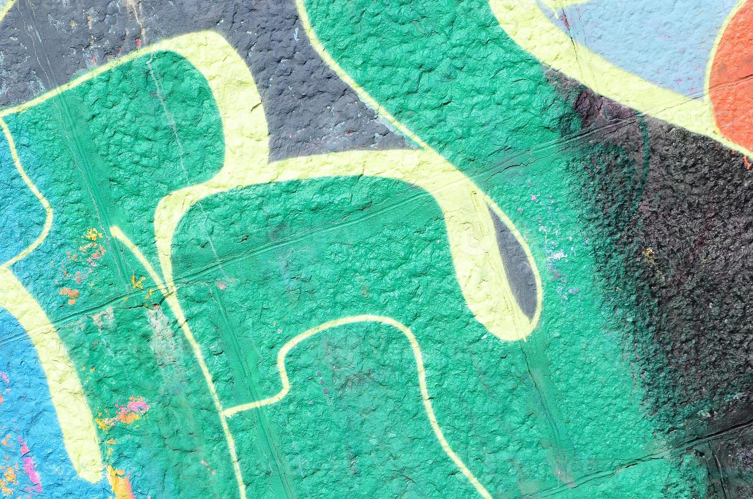 fragmento de dibujos de graffiti. la antigua muralla decorada con manchas de pintura al estilo de la cultura del arte callejero. textura de fondo coloreada en tonos verdes foto