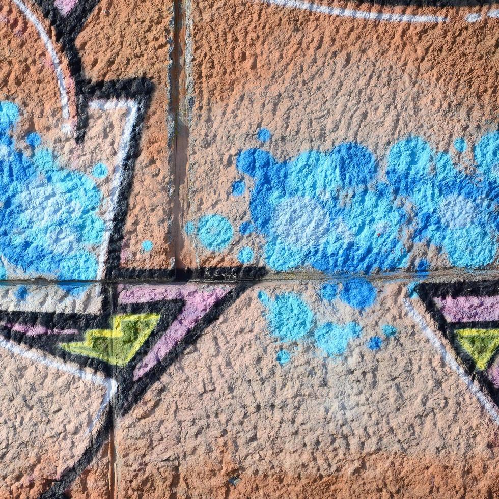 Fragment of graffiti drawings. The old wall decorated with paint stains in the style of street art culture. Colored background texture in warm tones photo
