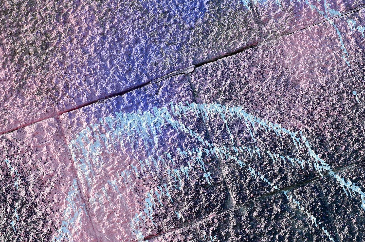 Fragment of graffiti drawings. The old wall decorated with paint stains in the style of street art culture. Colored background texture in purple tones photo