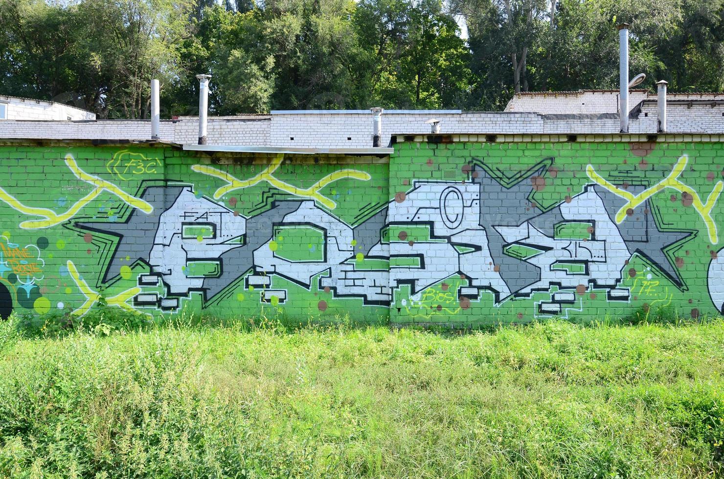 Fragment of graffiti drawings. The old wall decorated with paint stains in the style of street art culture. Colored background texture in green tones photo