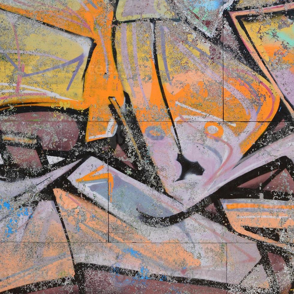 Fragment of graffiti drawings. The old wall decorated with paint stains in the style of street art culture. Colored background texture in warm tones photo