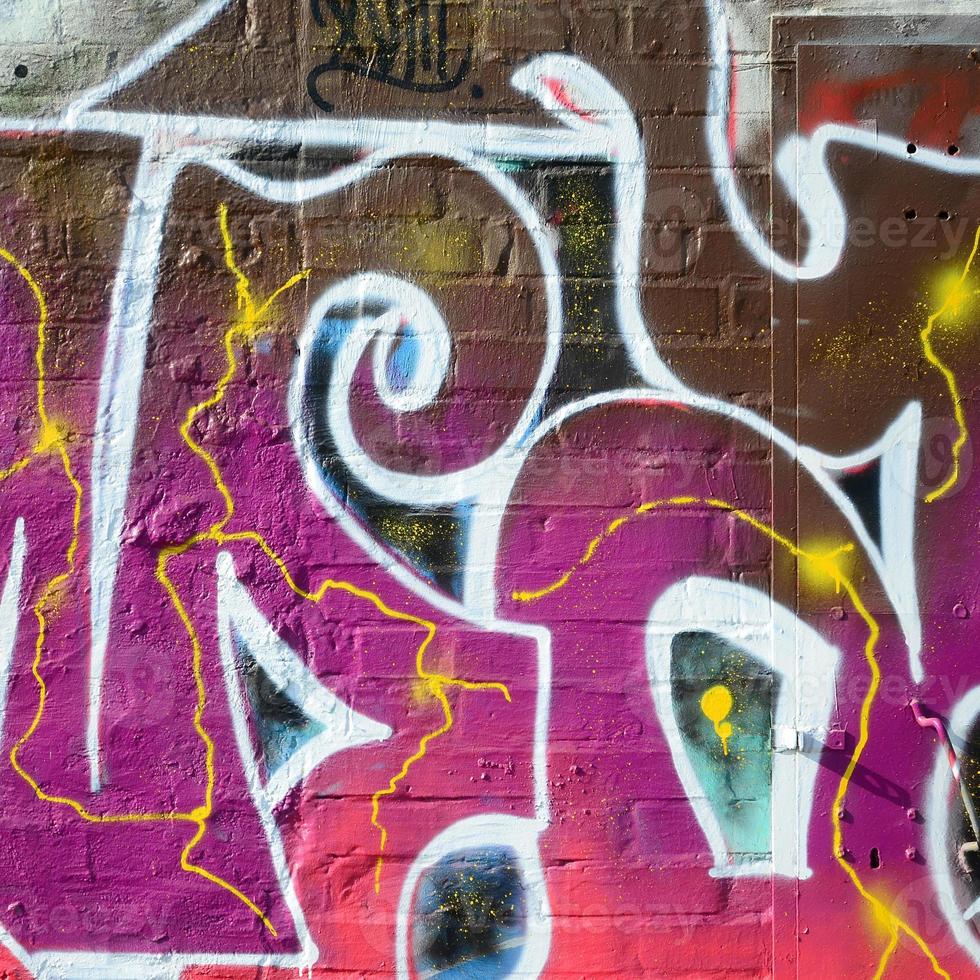 Fragment of graffiti drawings. The old wall decorated with paint stains in the style of street art culture. Colored background texture in warm tones photo