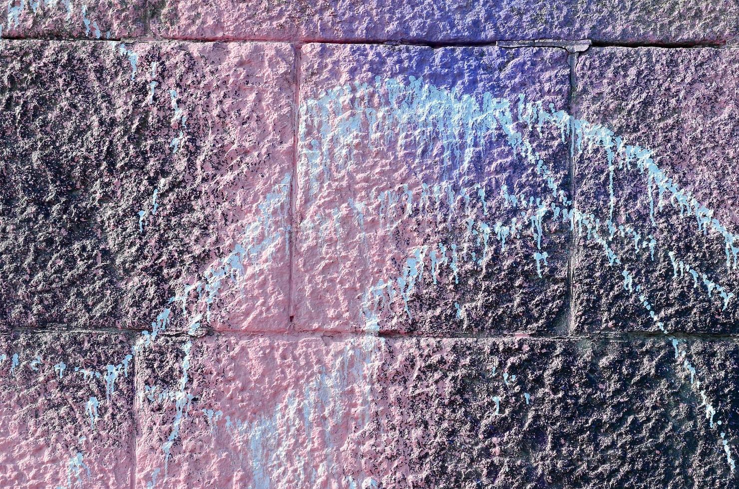 Fragment of graffiti drawings. The old wall decorated with paint stains in the style of street art culture. Colored background texture in purple tones photo