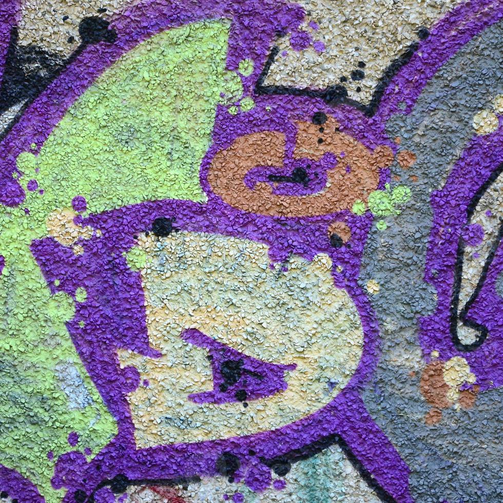 Fragment of graffiti drawings. The old wall decorated with paint stains in the style of street art culture. Colored background texture in warm tones photo