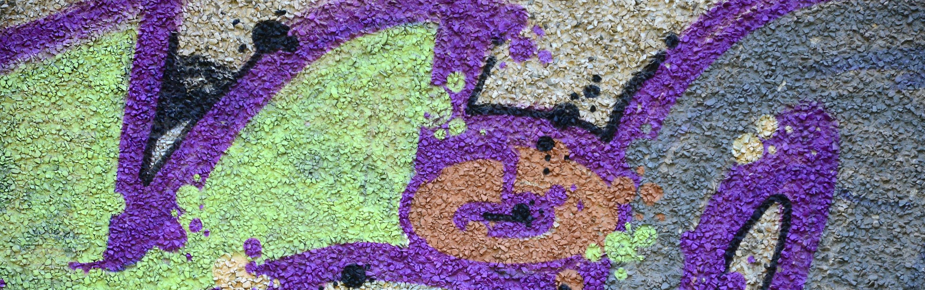 Fragment of graffiti drawings. The old wall decorated with paint stains in the style of street art culture. Colored background texture in warm tones photo