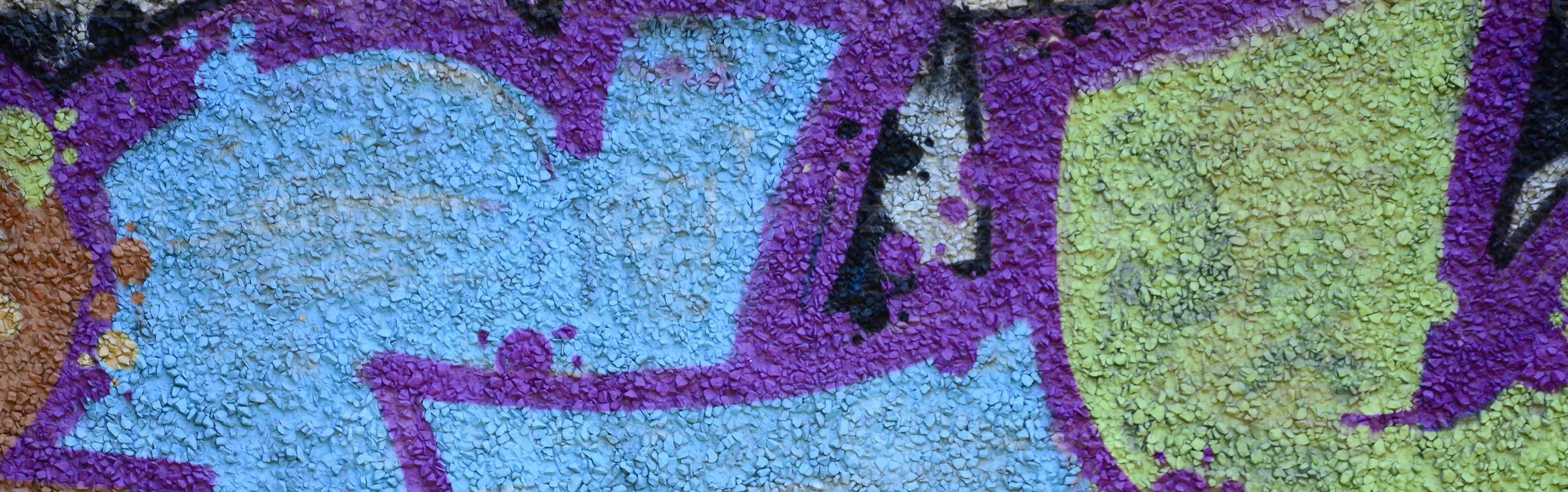 Fragment of graffiti drawings. The old wall decorated with paint stains in the style of street art culture. Colored background texture in warm tones photo