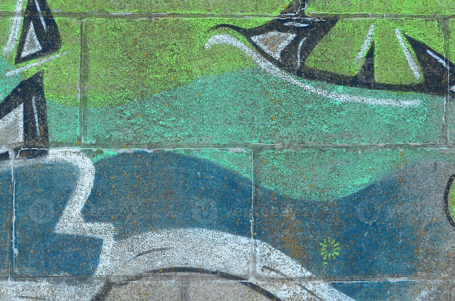 Fragment of graffiti drawings. The old wall decorated with paint stains in the style of street art culture. Colored background texture in green tones photo