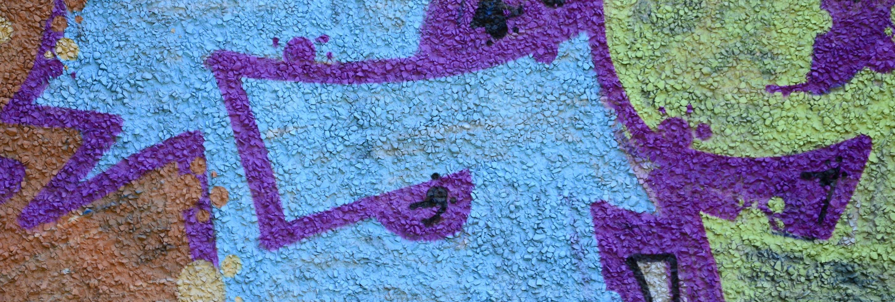 Fragment of graffiti drawings. The old wall decorated with paint stains in the style of street art culture. Colored background texture in warm tones photo