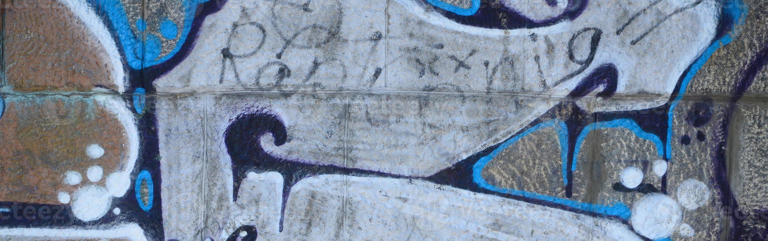 Fragment of graffiti drawings. The old wall decorated with paint stains in the style of street art culture. Colored background texture in warm tones photo