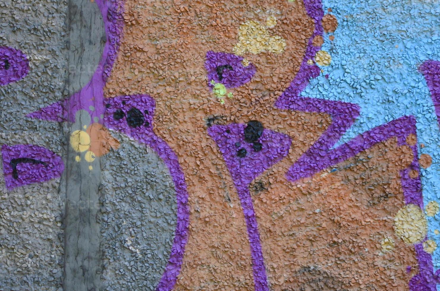Fragment of graffiti drawings. The old wall decorated with paint stains in the style of street art culture. Colored background texture in warm tones photo