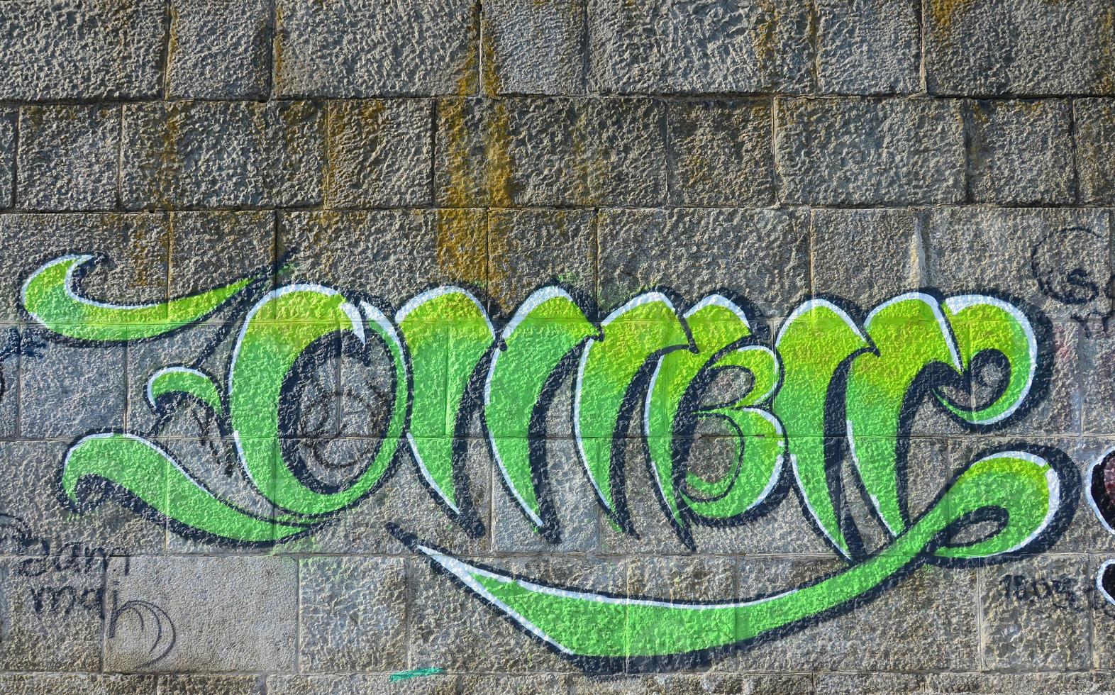 fragmento de dibujos de graffiti. la antigua muralla decorada con manchas de pintura al estilo de la cultura del arte callejero. textura de fondo coloreada en tonos verdes foto