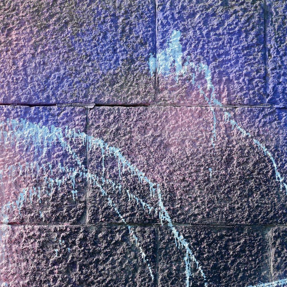 Fragment of graffiti drawings. The old wall decorated with paint stains in the style of street art culture. Colored background texture in purple tones photo