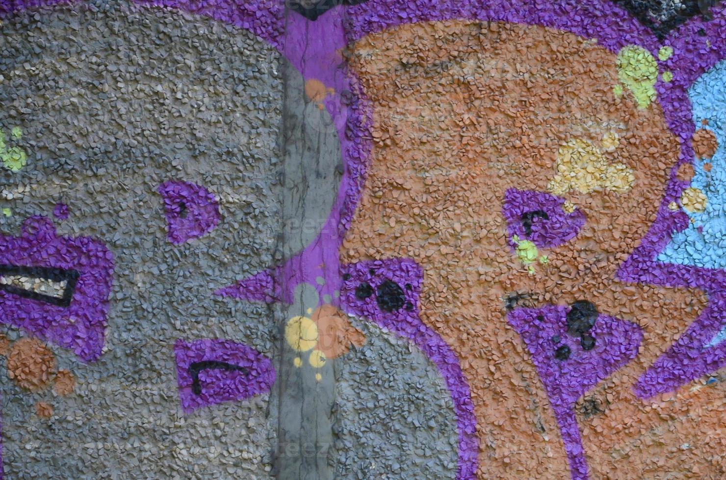 Fragment of graffiti drawings. The old wall decorated with paint stains in the style of street art culture. Colored background texture in warm tones photo