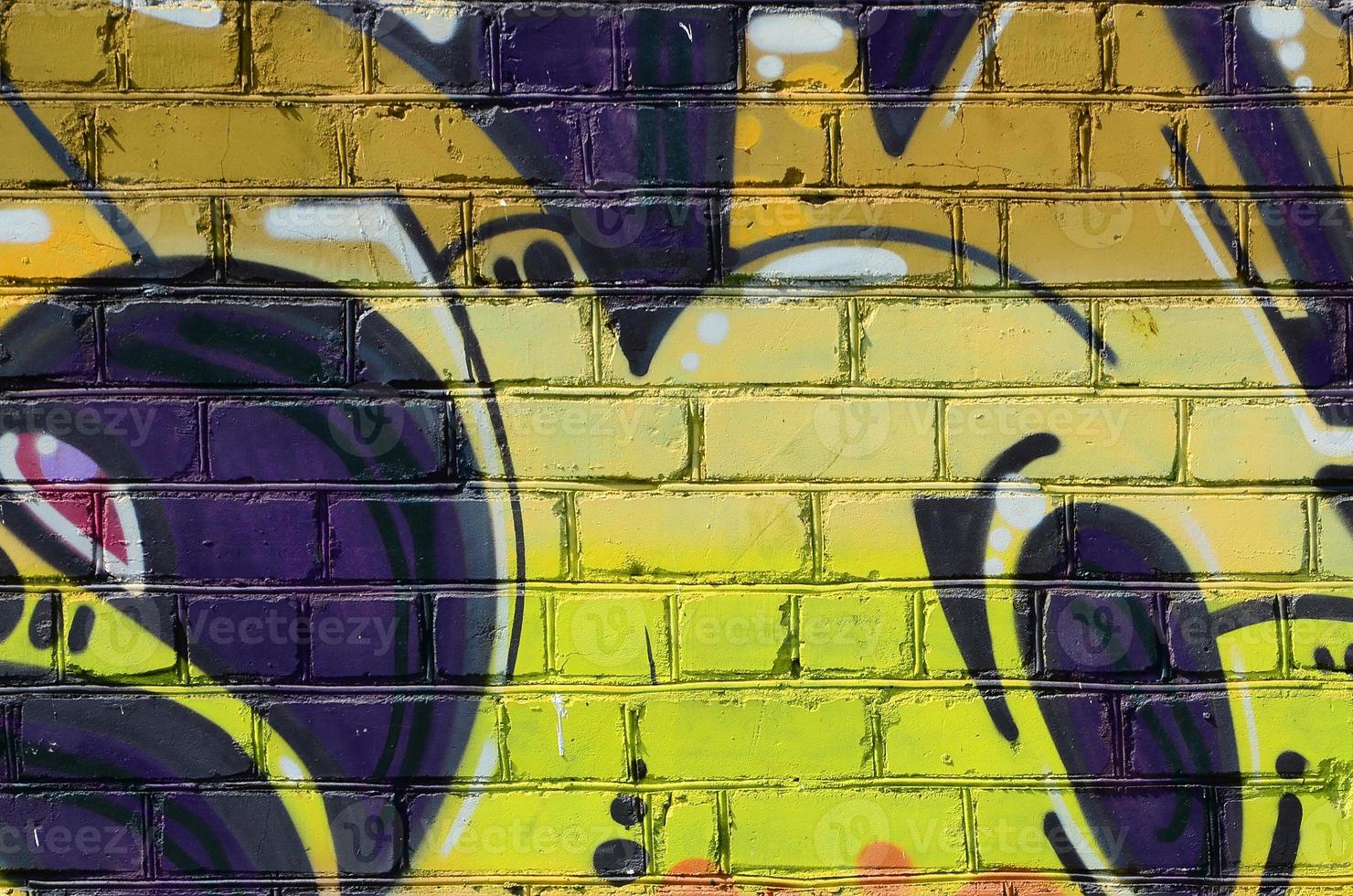 Fragment of graffiti drawings. The old wall decorated with paint stains in the style of street art culture. Colored background texture in warm tones photo