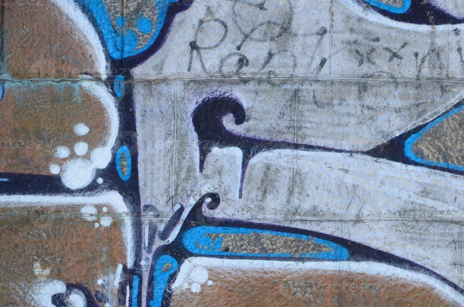 Fragment of graffiti drawings. The old wall decorated with paint stains in the style of street art culture. Colored background texture in warm tones photo