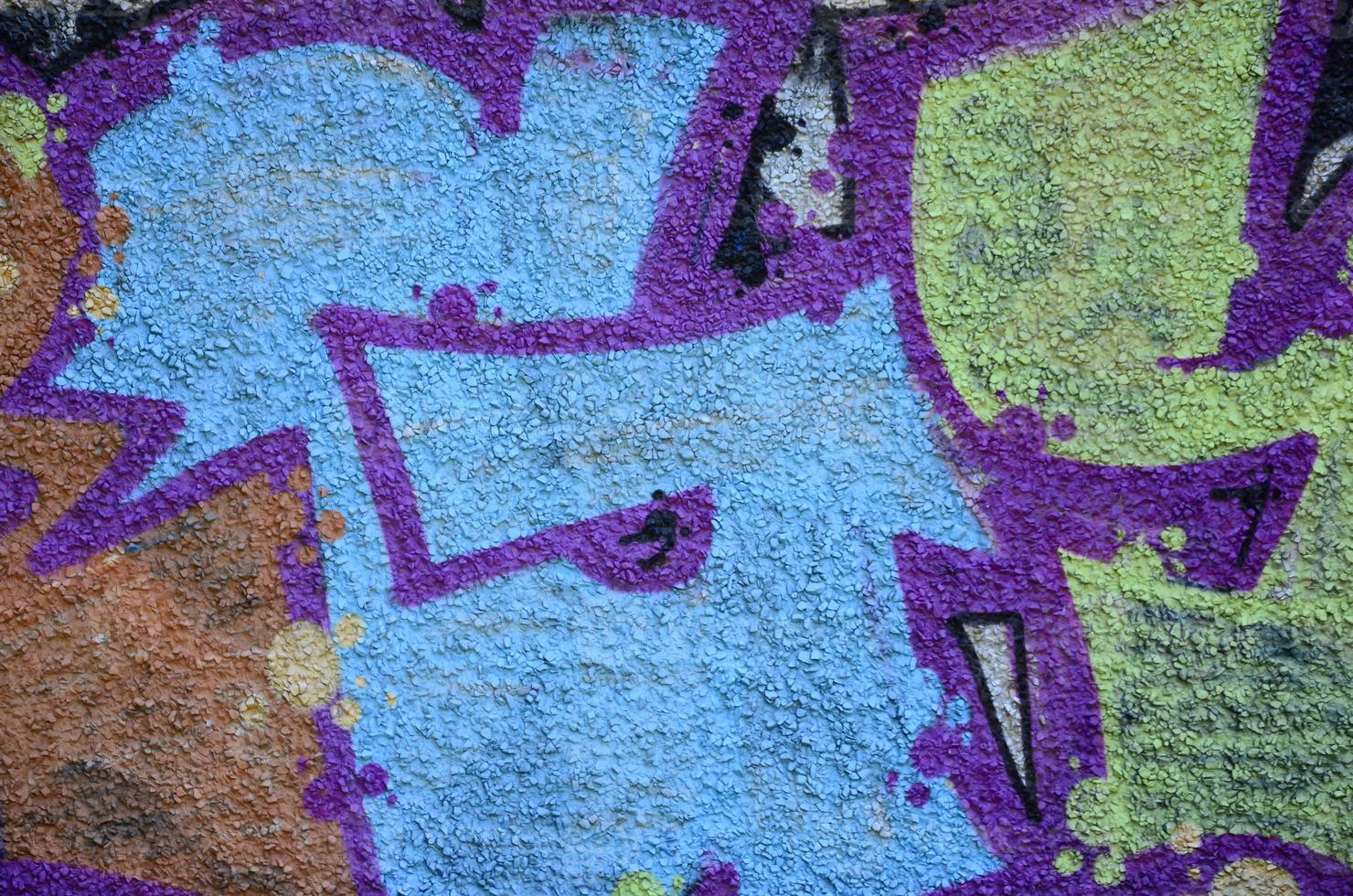 Fragment of graffiti drawings. The old wall decorated with paint stains in the style of street art culture. Colored background texture in warm tones photo