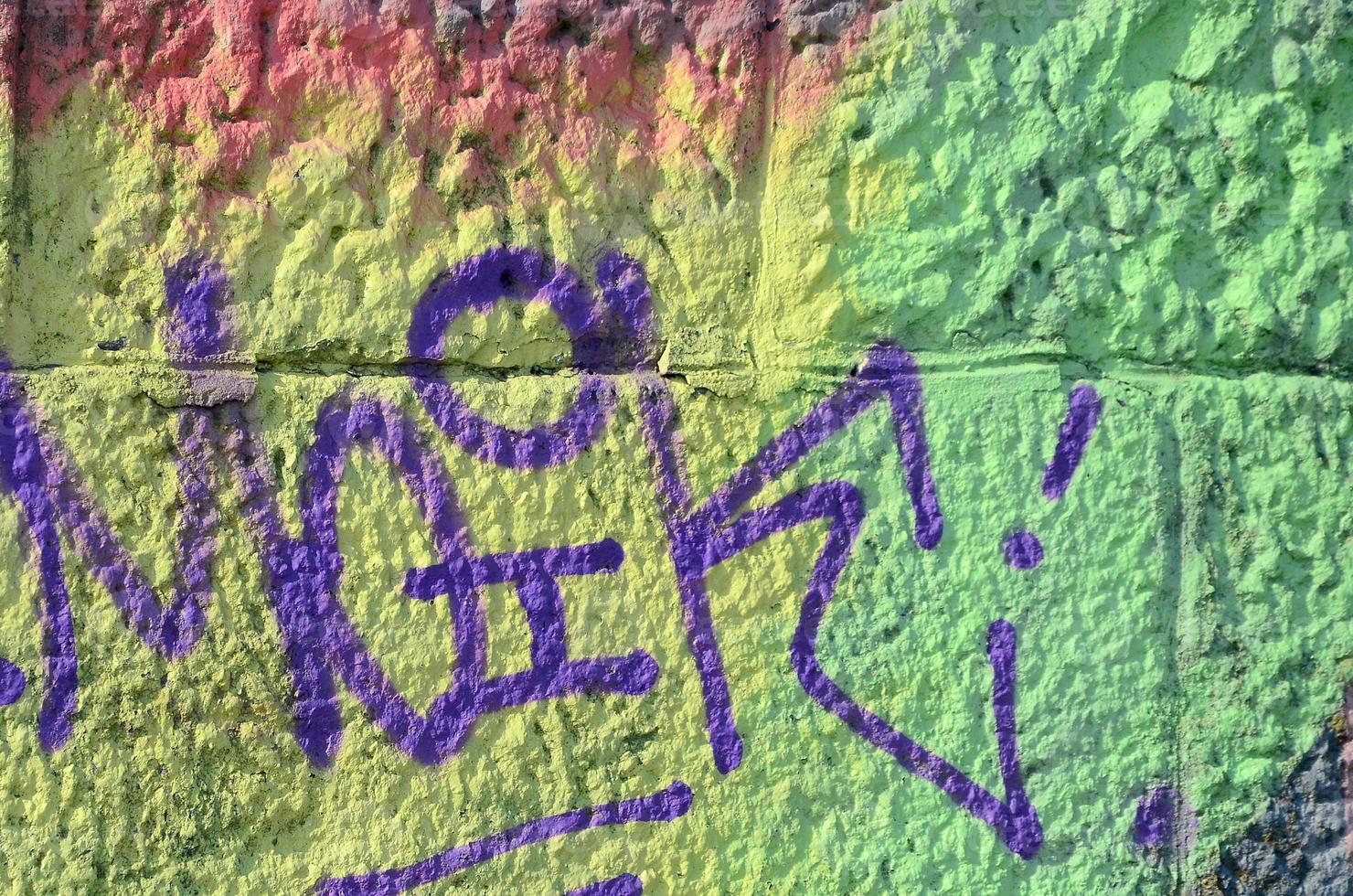 Fragment of graffiti drawings. The old wall decorated with paint stains in the style of street art culture. Colored background texture in warm tones photo