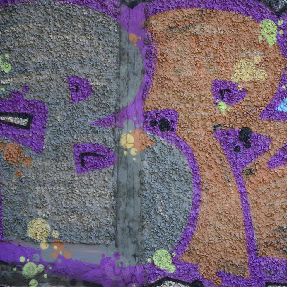 Fragment of graffiti drawings. The old wall decorated with paint stains in the style of street art culture. Colored background texture in warm tones photo