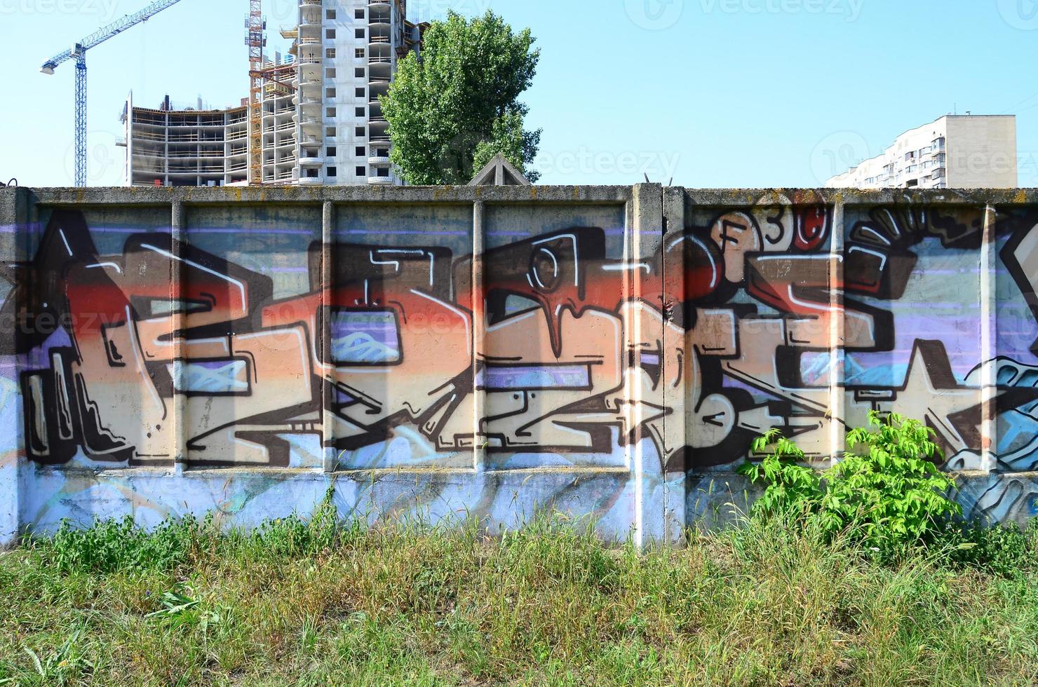 Fragment of graffiti drawings. The old wall decorated with paint stains in the style of street art culture. Colored background texture in warm tones photo