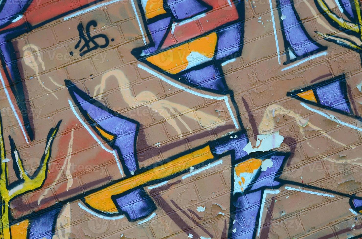 Fragment of graffiti drawings. The old wall decorated with paint stains in the style of street art culture. Colored background texture in warm tones photo