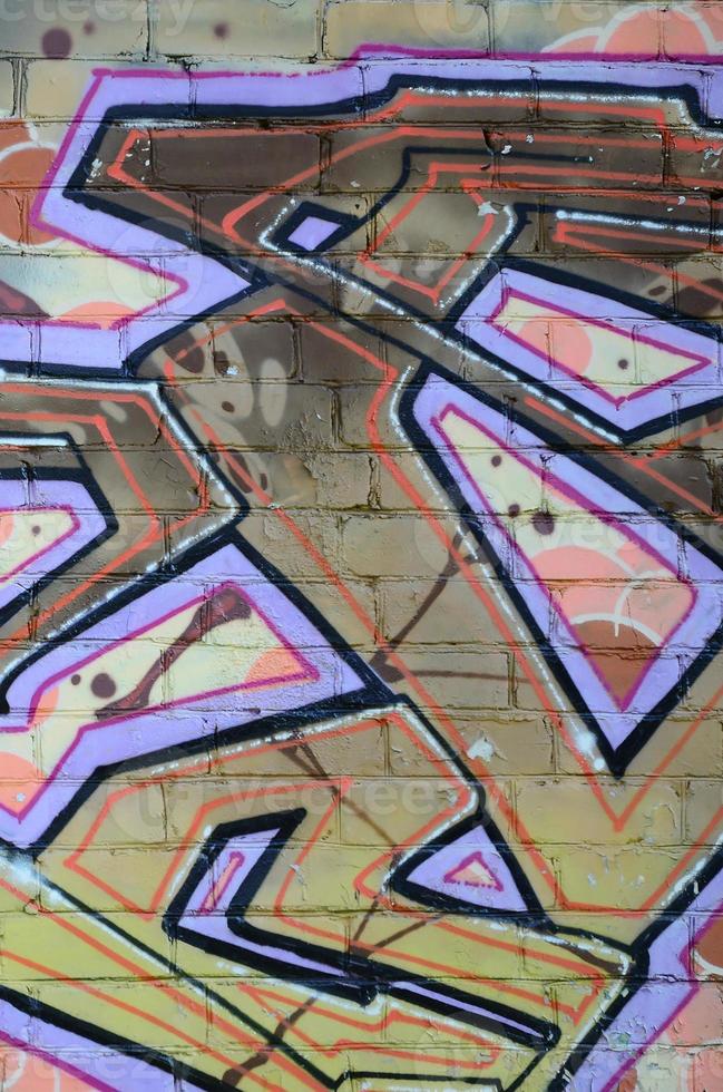 Fragment of graffiti drawings. The old wall decorated with paint stains in the style of street art culture. Colored background texture in warm tones photo