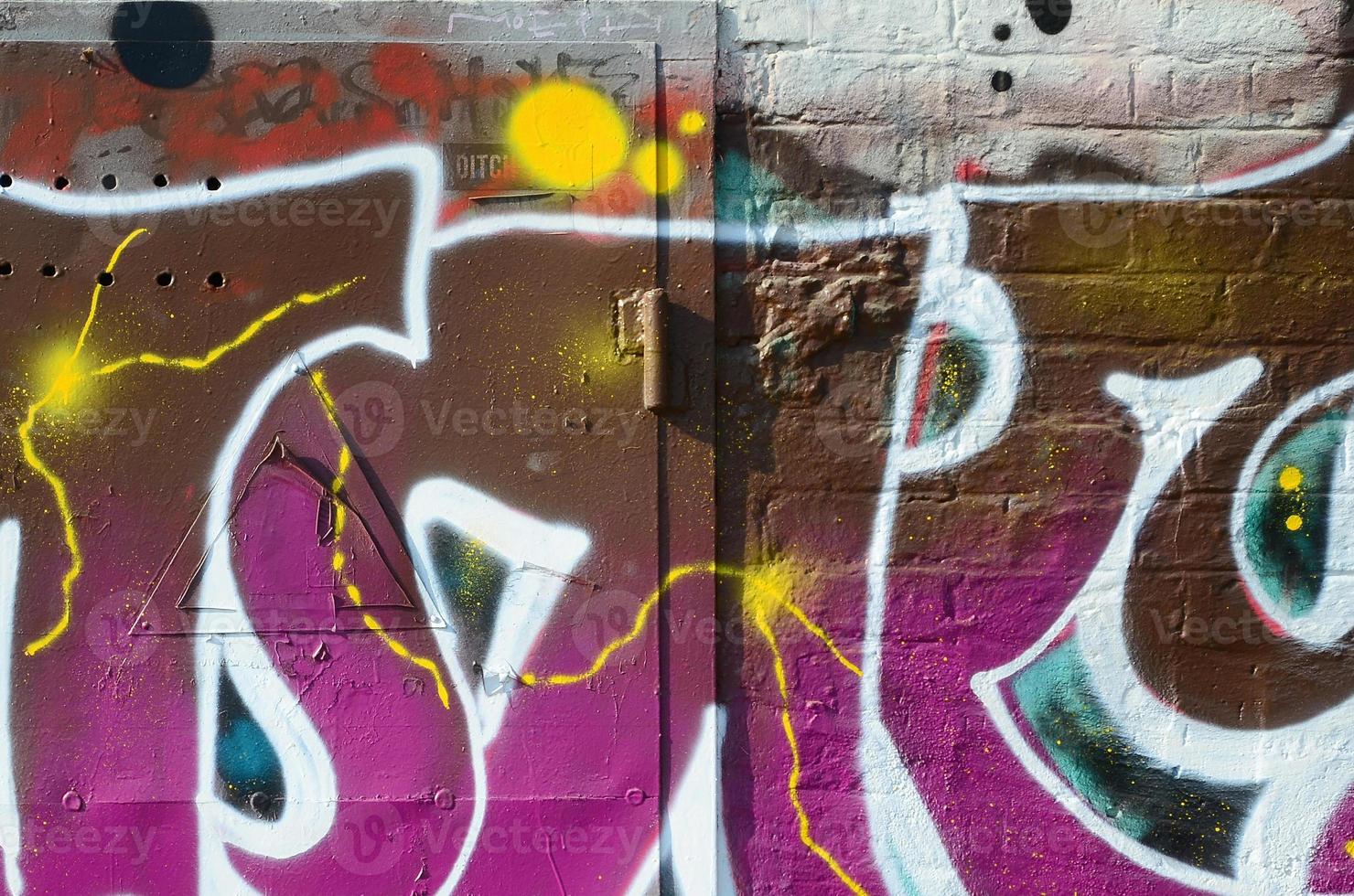 Fragment of graffiti drawings. The old wall decorated with paint stains in the style of street art culture. Colored background texture in warm tones photo