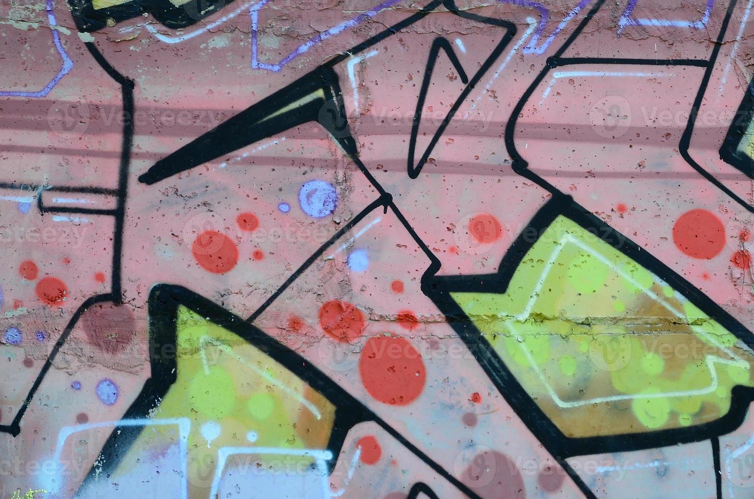 Fragment of graffiti drawings. The old wall decorated with paint stains in the style of street art culture. Colored background texture in warm tones photo