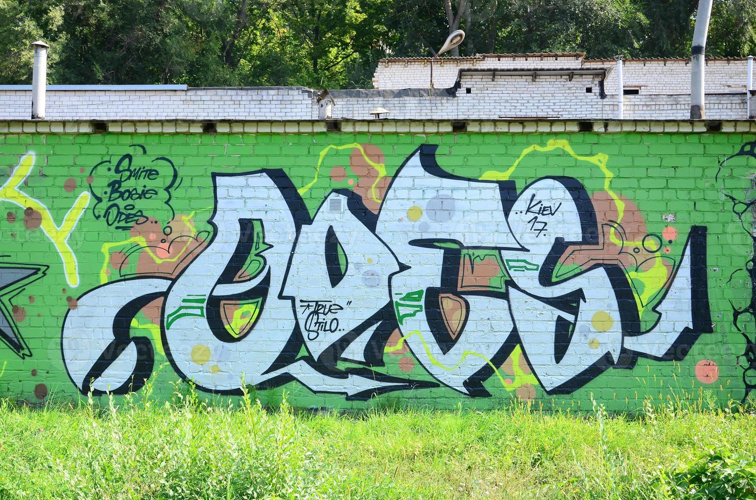 fragmento de dibujos de graffiti. la antigua muralla decorada con manchas de pintura al estilo de la cultura del arte callejero. textura de fondo coloreada en tonos verdes foto