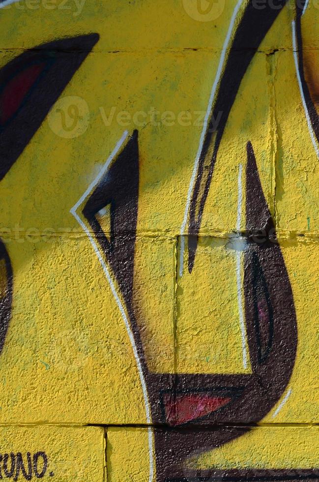 fragmento de dibujos de graffiti. la antigua muralla decorada con manchas de pintura al estilo de la cultura del arte callejero. textura de fondo coloreada en tonos cálidos foto