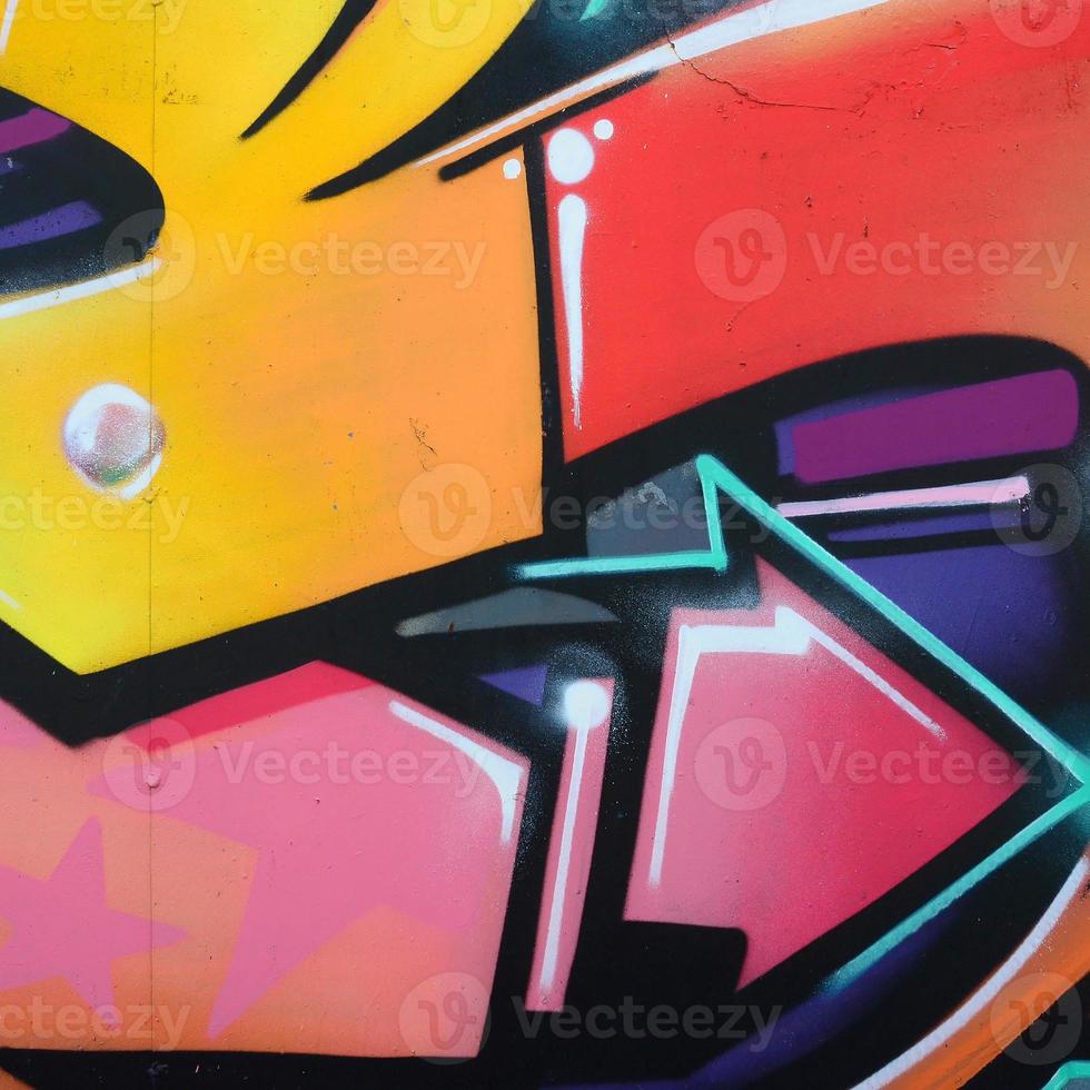 Fragment of graffiti drawings. The old wall decorated with paint stains in the style of street art culture. Colored background texture in warm tones photo