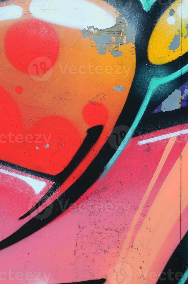 Fragment of graffiti drawings. The old wall decorated with paint stains in the style of street art culture. Colored background texture in warm tones photo