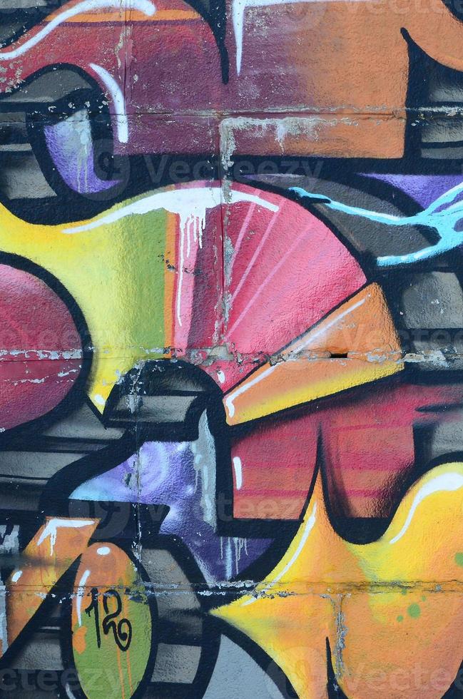 Fragment of graffiti drawings. The old wall decorated with paint stains in the style of street art culture. Colored background texture in warm tones photo