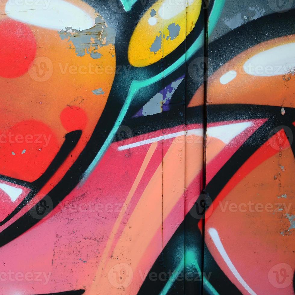 Fragment of graffiti drawings. The old wall decorated with paint stains in the style of street art culture. Colored background texture in warm tones photo