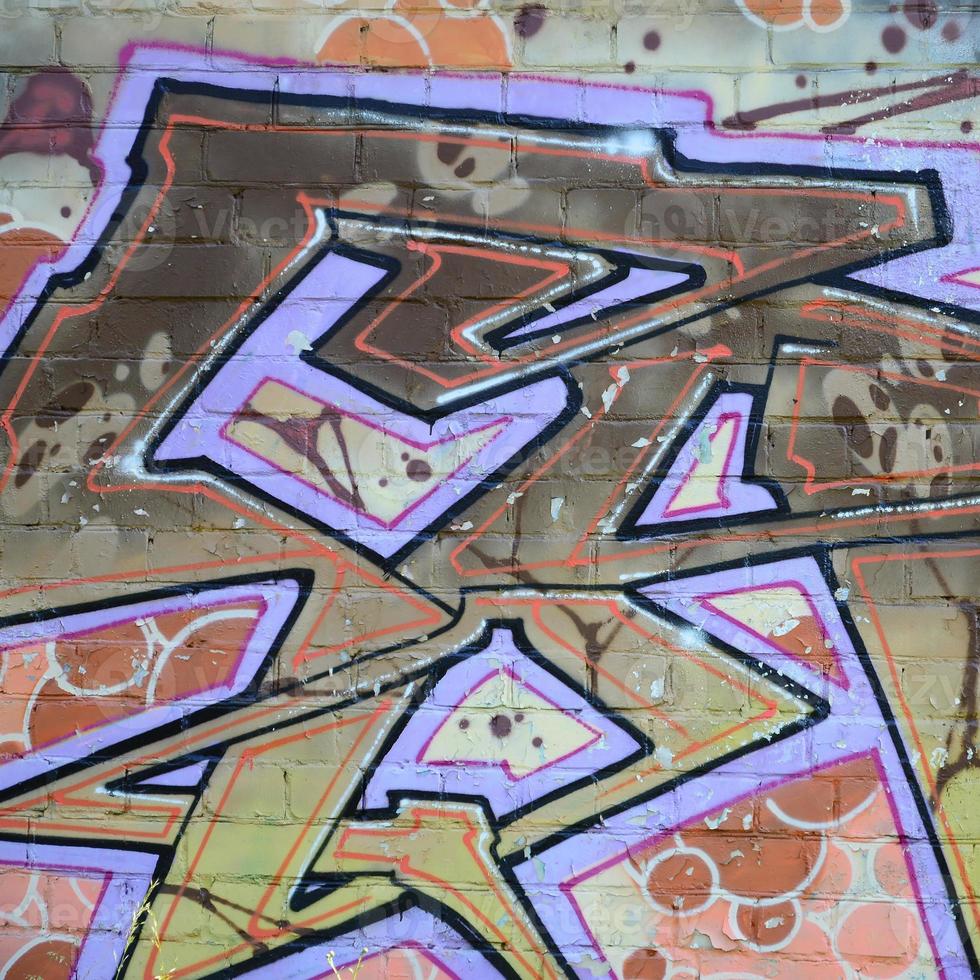 Fragment of graffiti drawings. The old wall decorated with paint stains in the style of street art culture. Colored background texture in warm tones photo