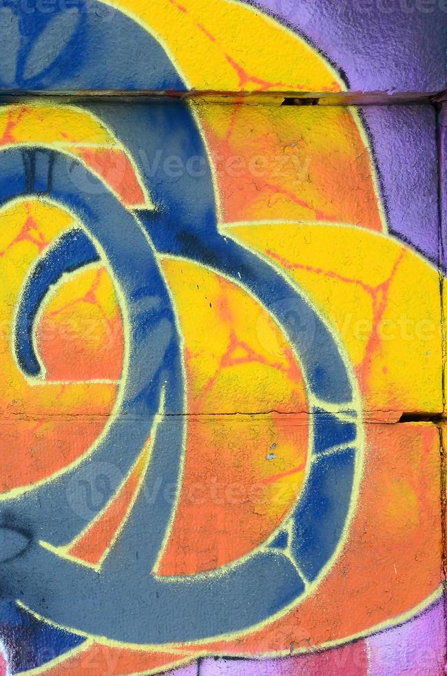 Fragment of graffiti drawings. The old wall decorated with paint stains in the style of street art culture. Colored background texture in warm tones photo