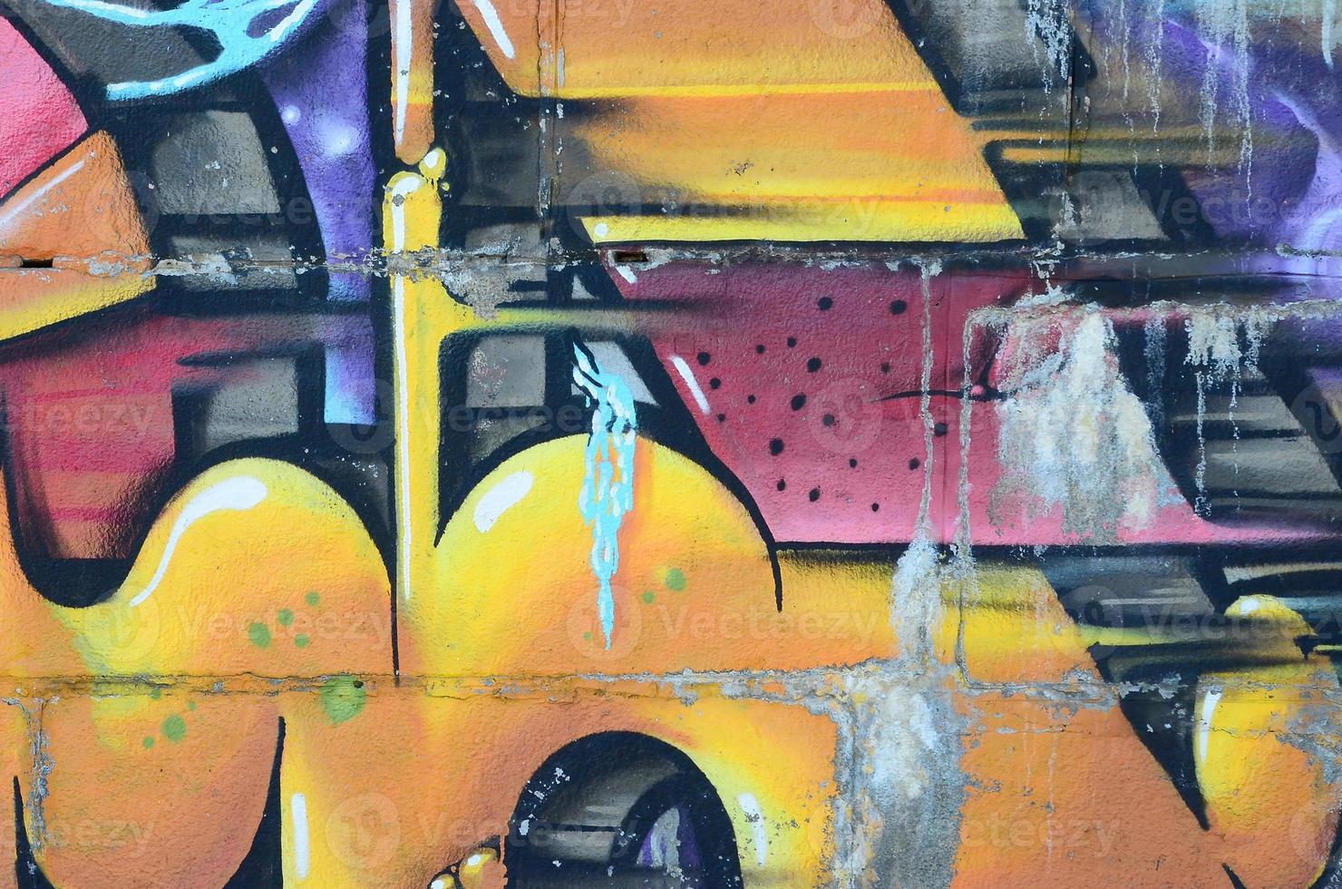 Fragment of graffiti drawings. The old wall decorated with paint stains in the style of street art culture. Colored background texture in warm tones photo