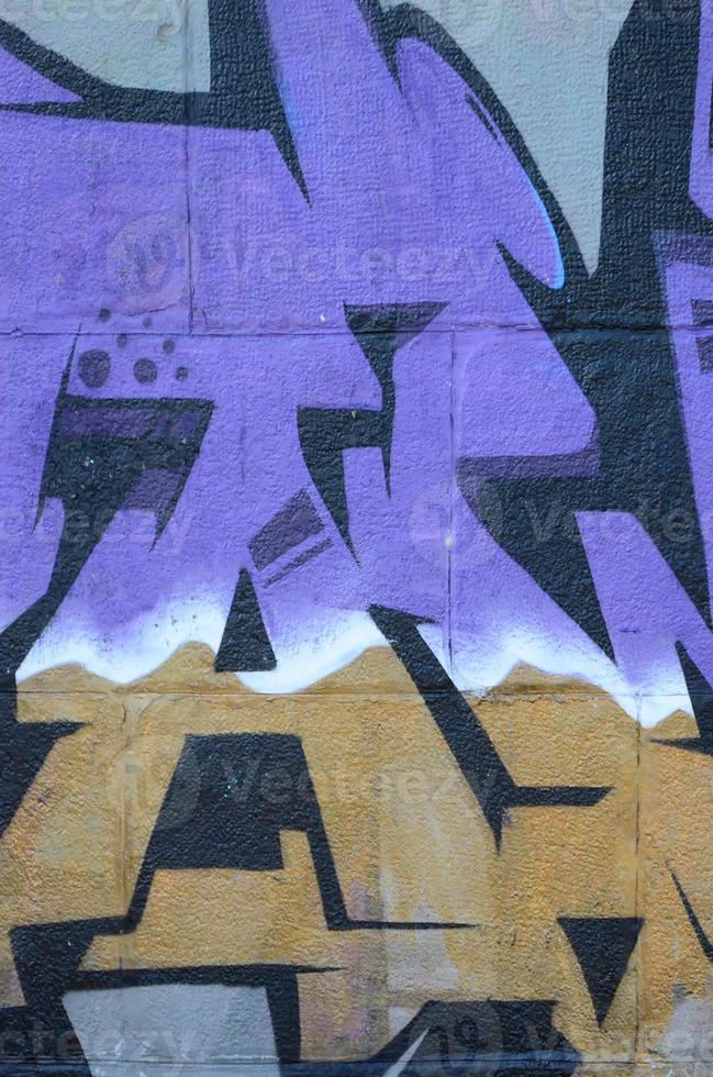 fragmento de dibujos de graffiti. la antigua muralla decorada con manchas de pintura al estilo de la cultura del arte callejero. textura de fondo coloreada en tonos morados foto