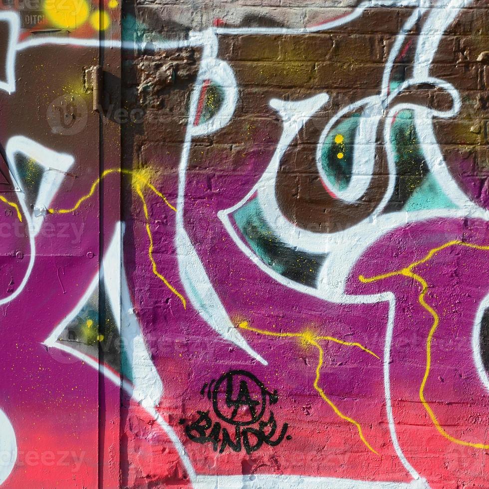 Fragment of graffiti drawings. The old wall decorated with paint stains in the style of street art culture. Colored background texture in warm tones photo