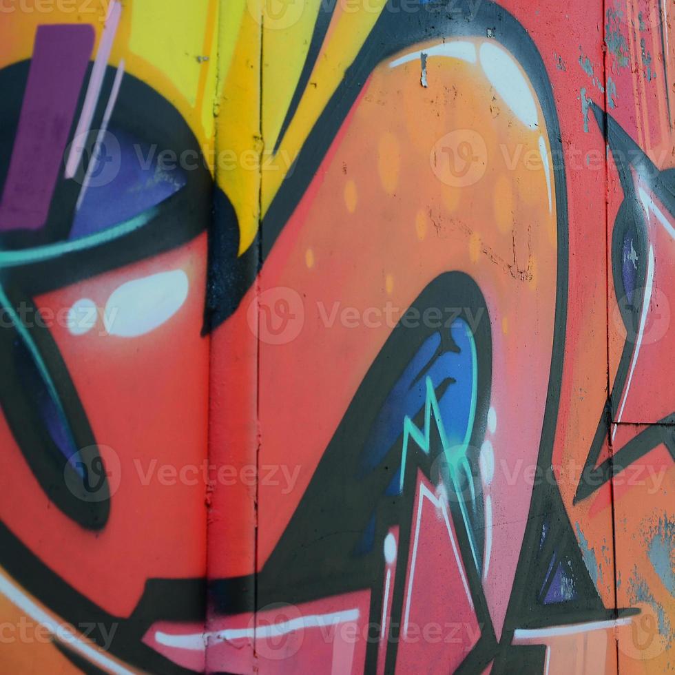 Fragment of graffiti drawings. The old wall decorated with paint stains in the style of street art culture. Colored background texture in warm tones photo